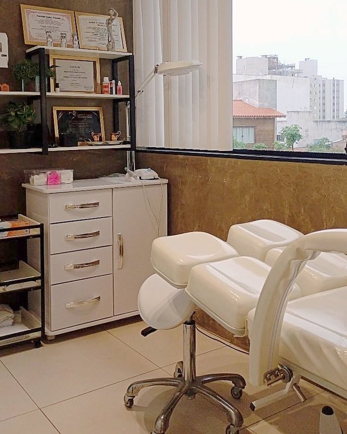 Sala de atendimento do consultório, com maca reclinável, luminária com lupa e armário de instrumentos